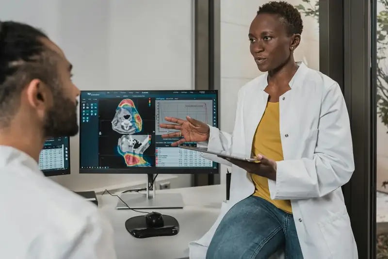 Clinicians speaking in a medical office beside diagnostic screens